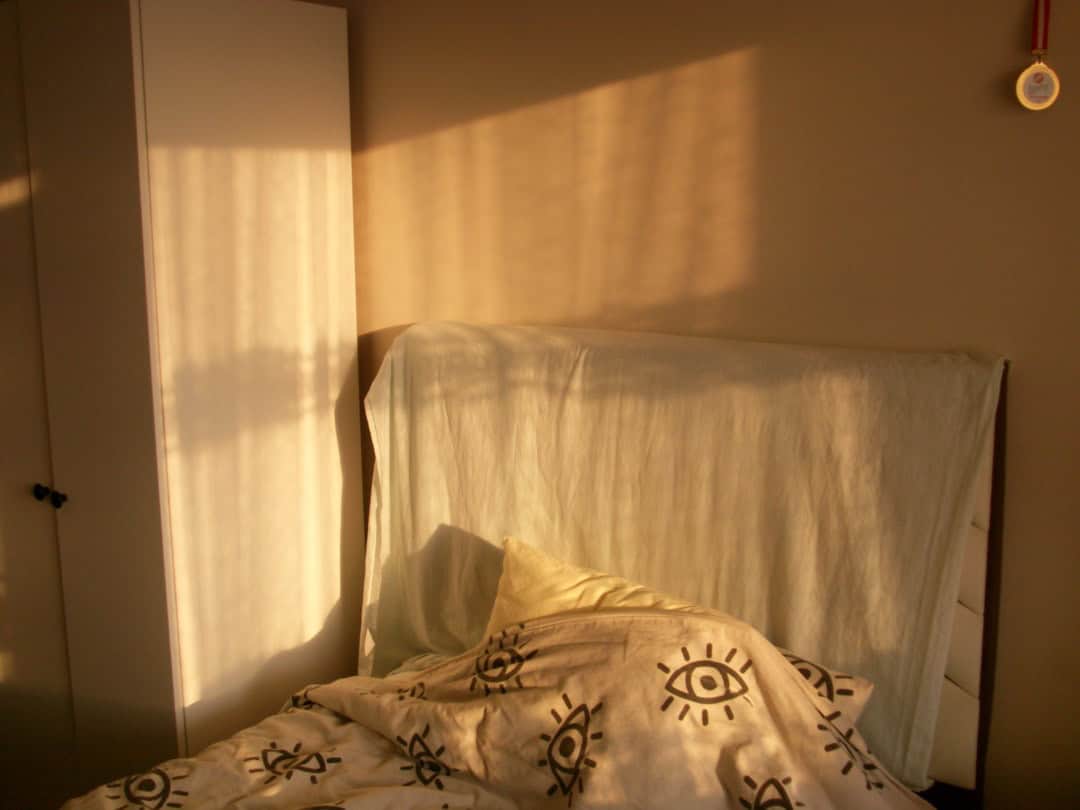 Ruhig beleuchtetes Schlafzimmer mit warmer Lampe und aufgeschlagenem Buch als Teil einer Abendroutine für besseren Schlaf
