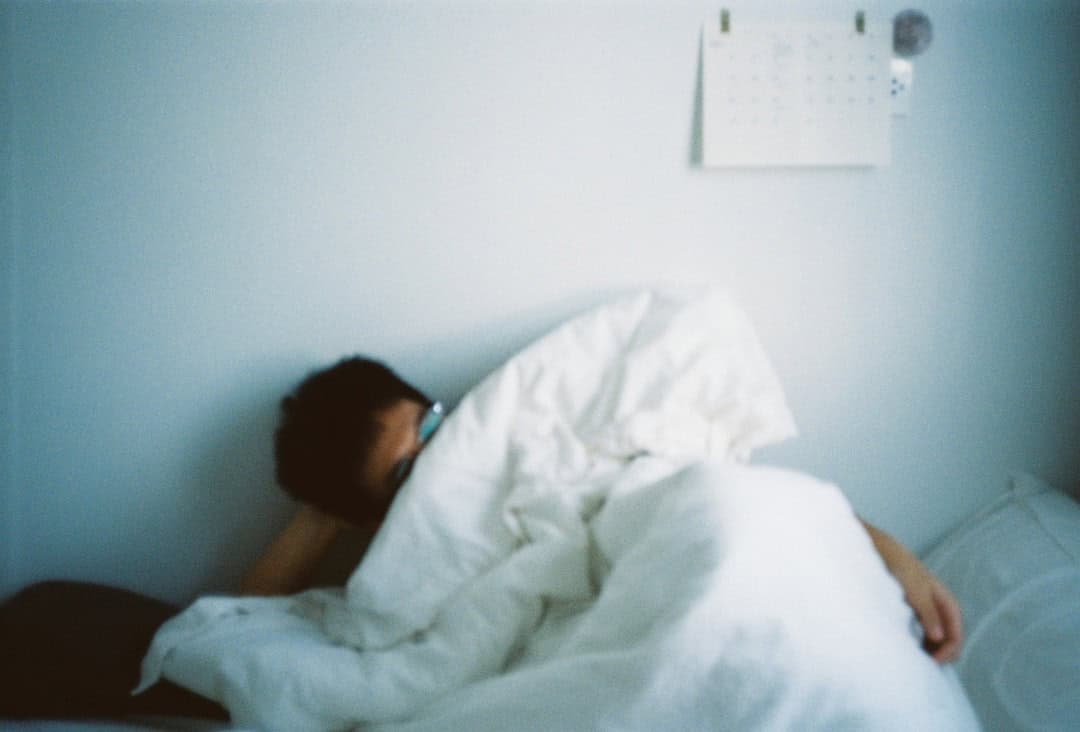 Person liegt nachts wach im Bett mit offenen Augen – Einschlafprobleme und Schlafstörungen