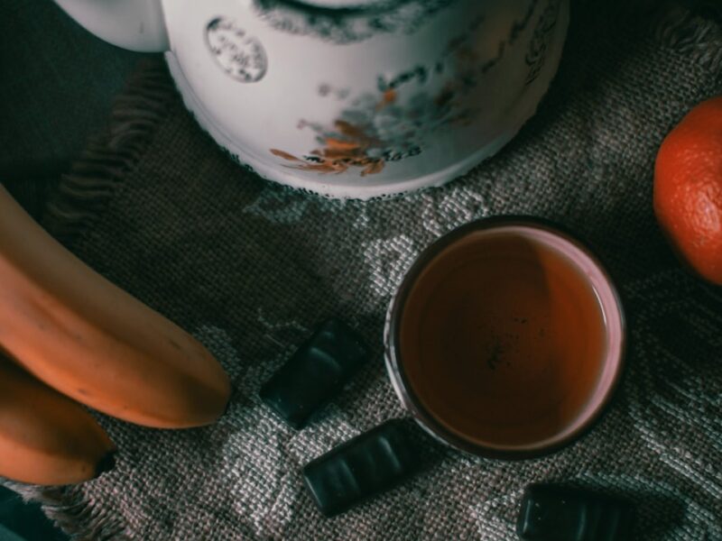 Tasse Bananentee mit Zimtstange auf einem Holztisch, weiches Abendlicht — natürliches Hausmittel gegen Schlaflosigkeit