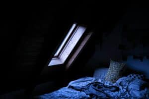 Kühles Schlafzimmer mit Thermometer auf dem Nachttisch — optimale Schlaftemperatur 18 Grad