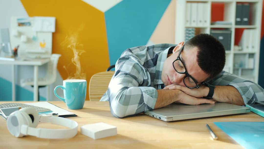 Person macht einen 20-minütigen Powernap am Schreibtisch im hellen Büro